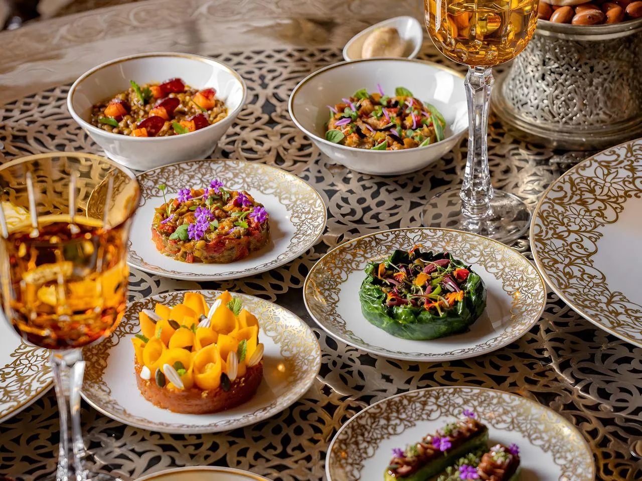 Traiteur mariage à Marrakech, plats colorés sur une table aux assiettes dorées et verres ambrés